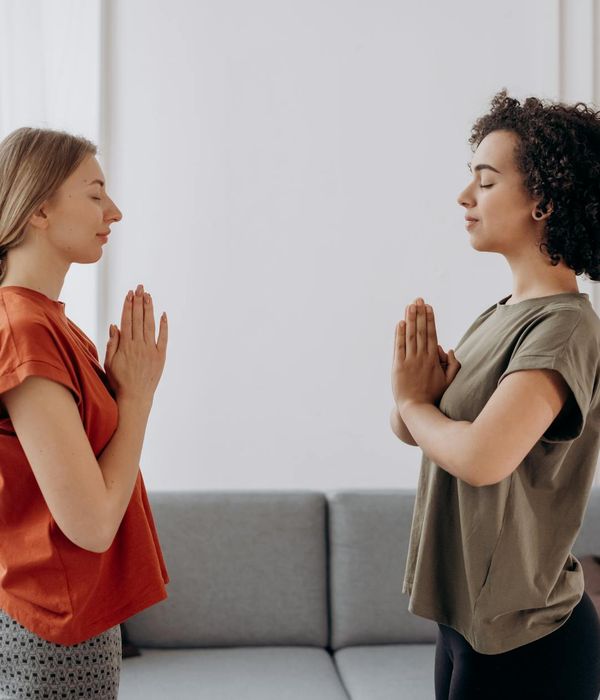 Woman in a calming yoga pose in a softly lit room.